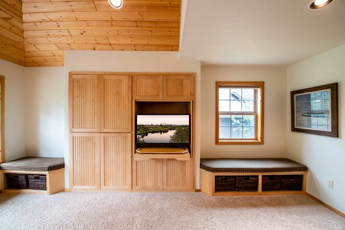 A comfortable seating area with wooden cabinetry, a TV, and large windows offering sunset views. The atmosphere is inviting and ideal for relaxing after a day of adventure, watching shows together, or enjoying shared laughter during movie nights.