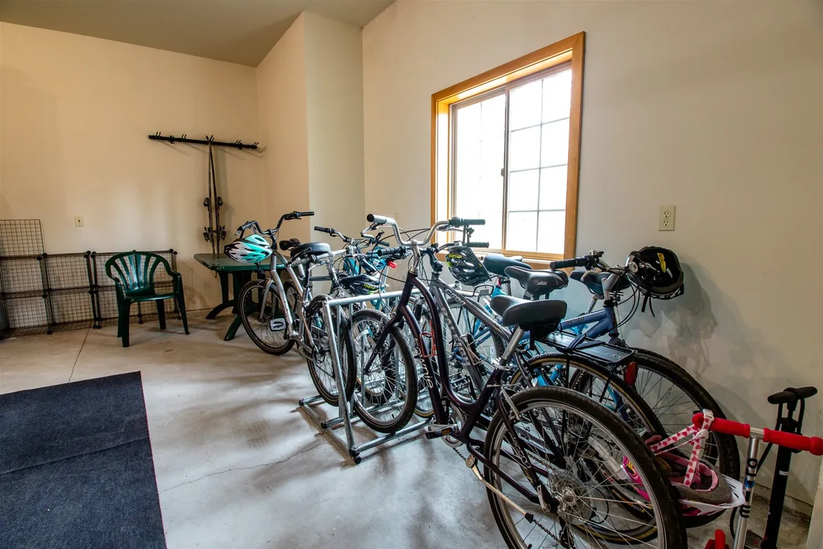 A bright garage area featuring bicycles, a window, and a work table, exuding an active and practical vibe. The presence of bikes and workspace suggests easy access to trails and preparation for outdoor excursions.